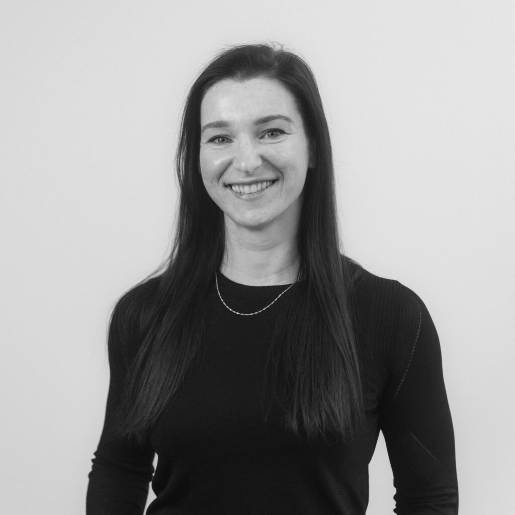 Black and white portrait of Caro Coox, managing partner of Customer Link, smiling straight into the camera