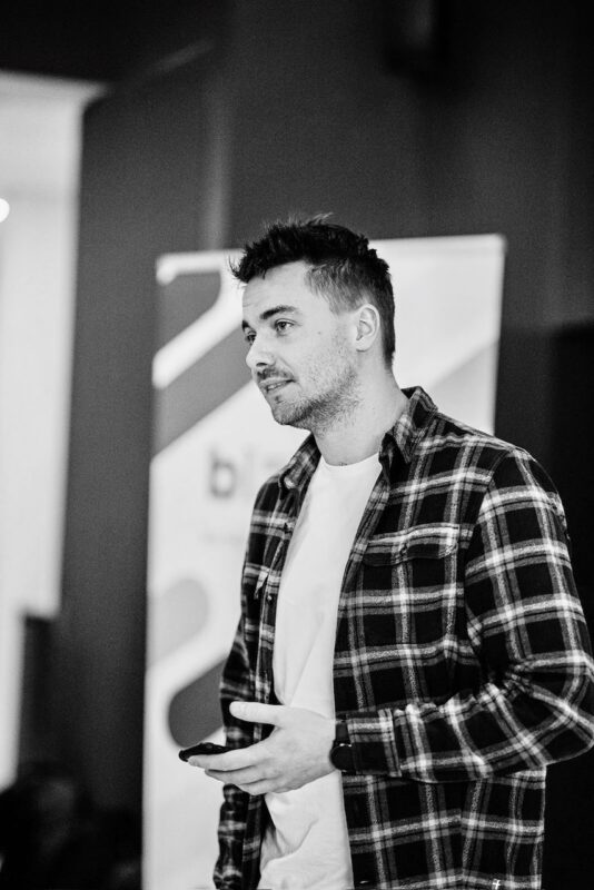Black-and-white image of Nicolas Beunen giving a presentation, standing in front of a Biztory banner.