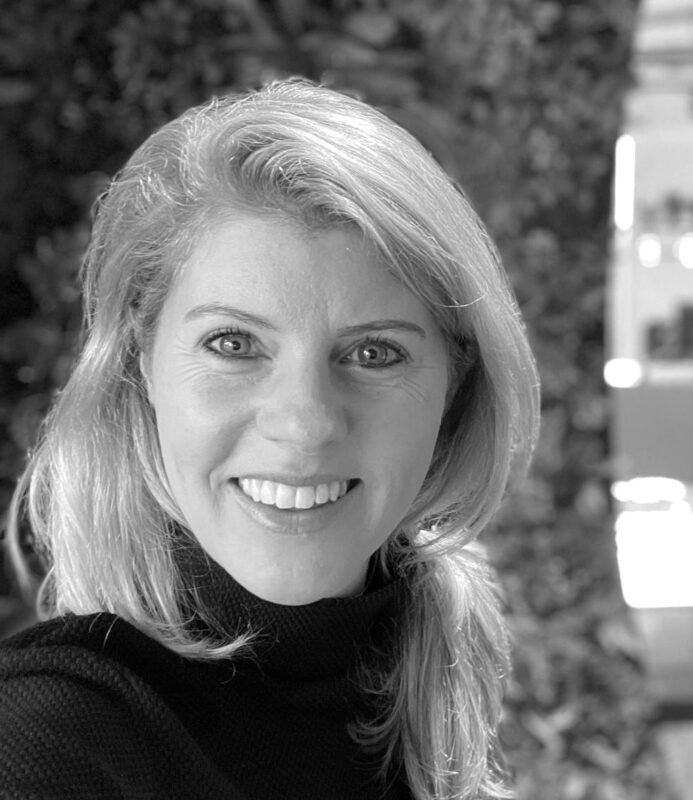 Portrait of Annemieke Klok smiling, wearing a dark top in front of a blurred background.