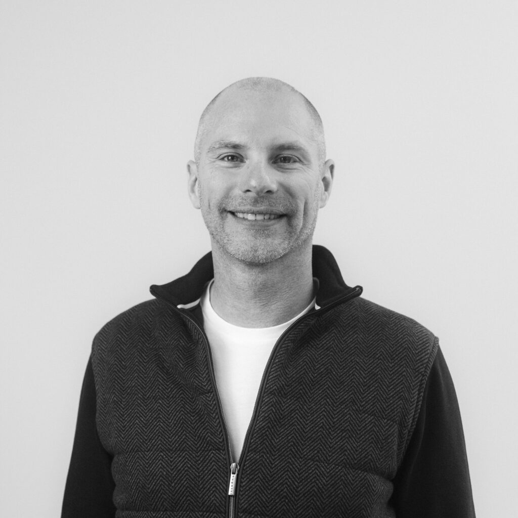 A black and white portrait of Jarno Moermans, smiling an looking straight into the camera